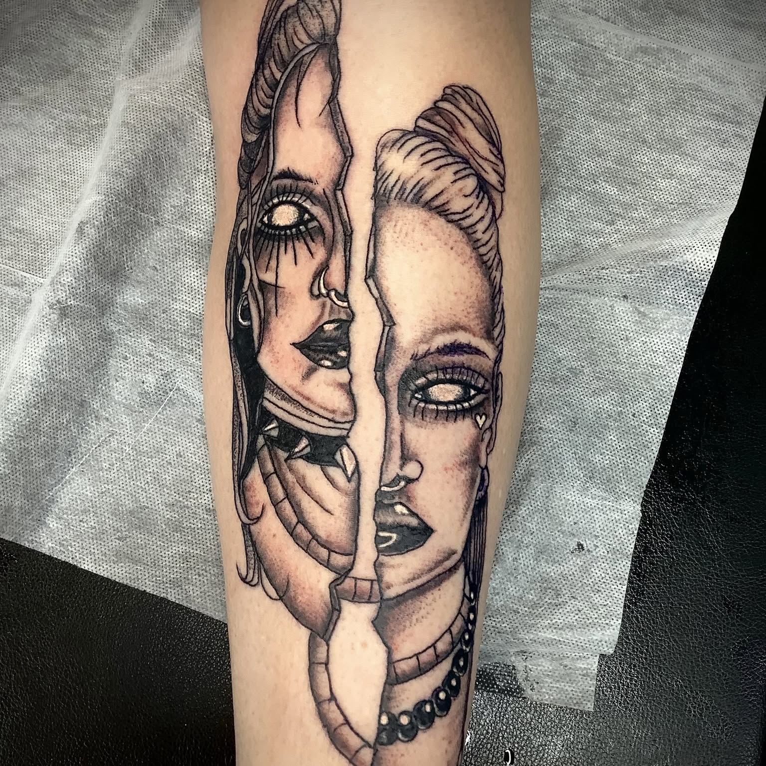 Black and grey split face portrait tattoo on a forearm