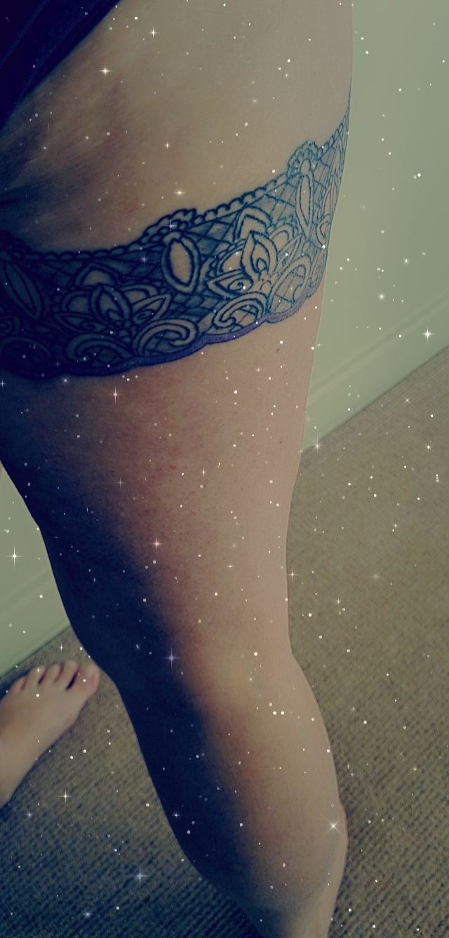 Lace garter tattoo around a thigh
